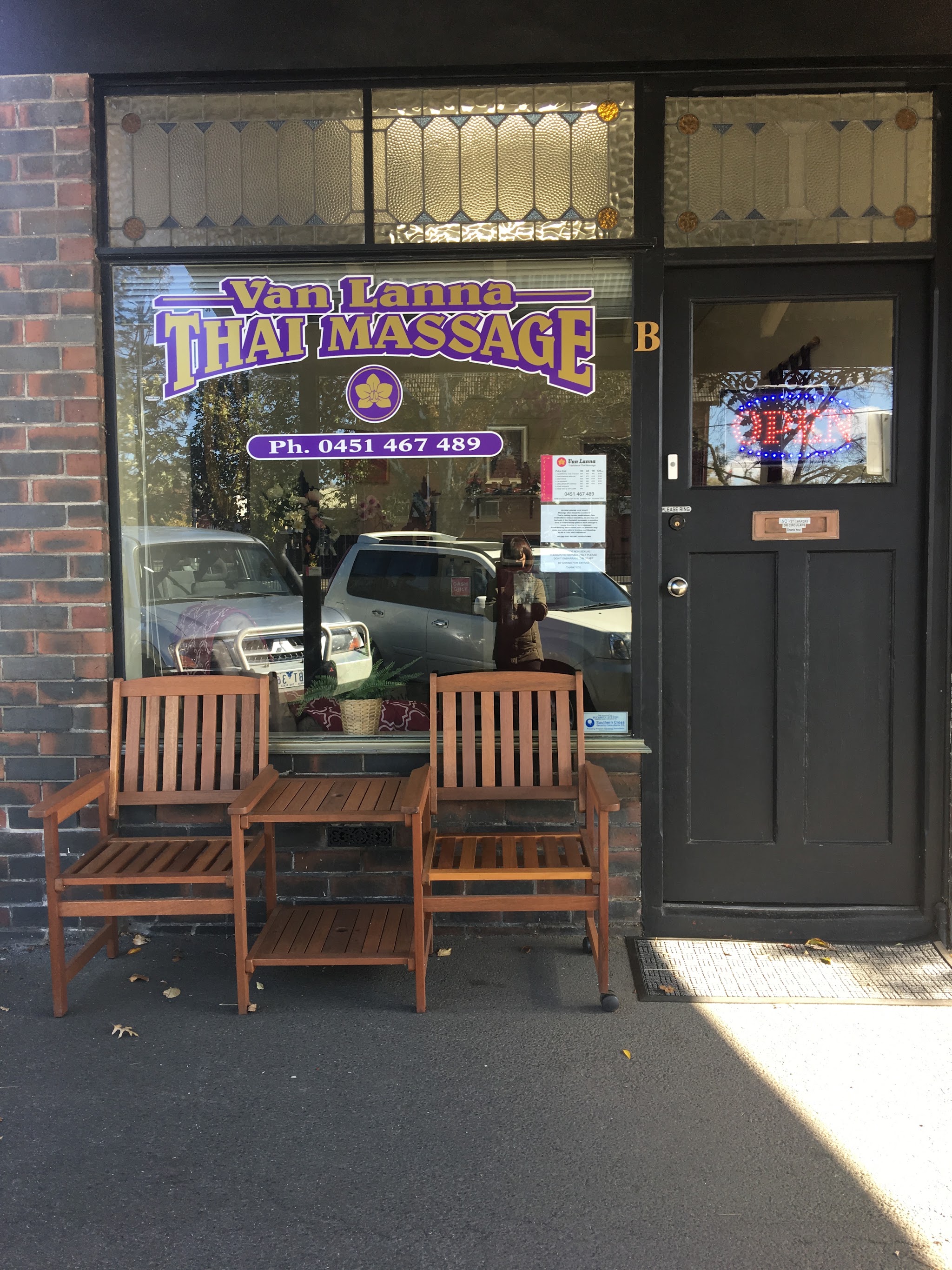 Close view of the Van Lanna window signage with the phone number and timber benches