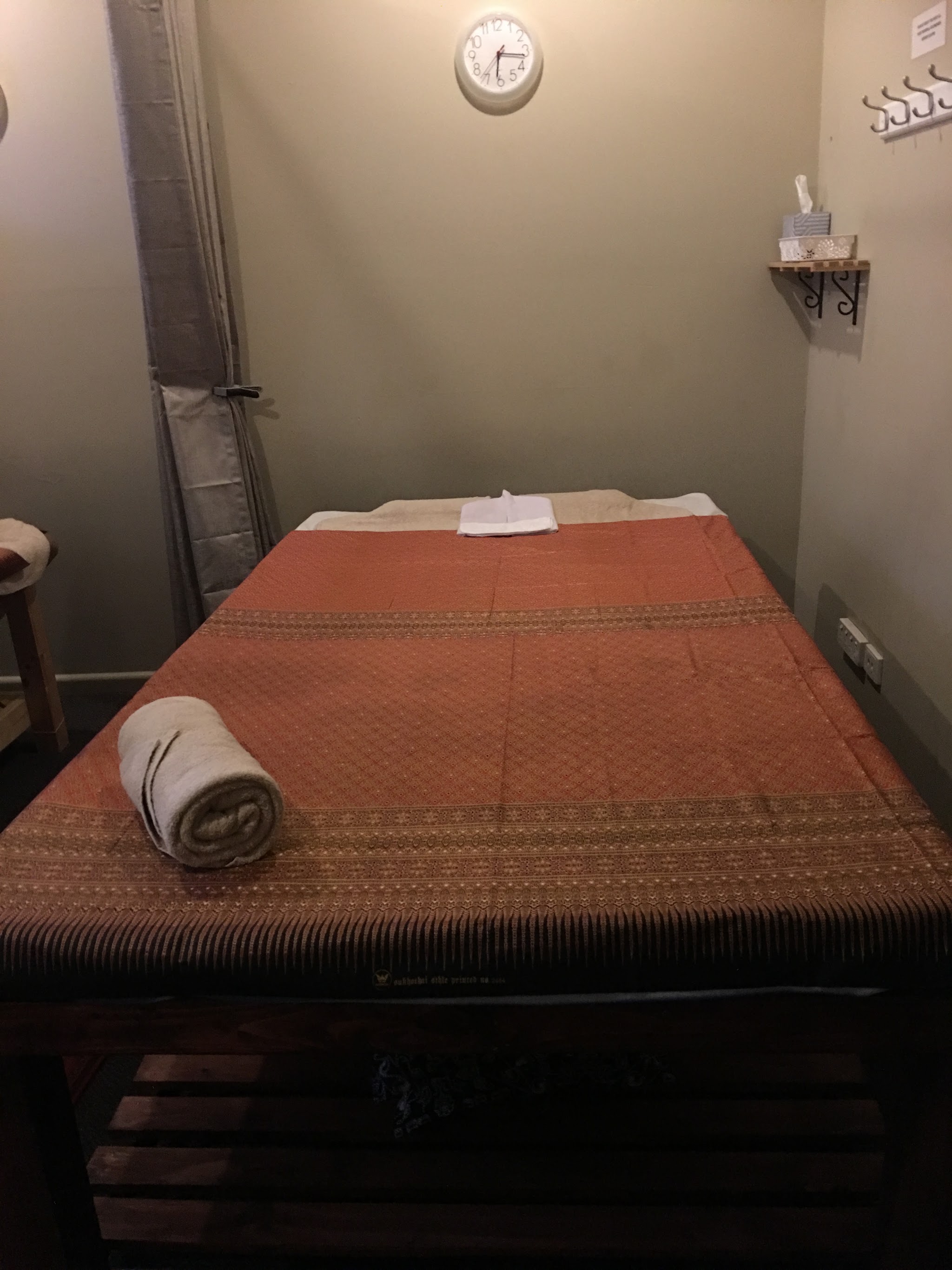 A second treatment room with a rust Thai-pattern table cover